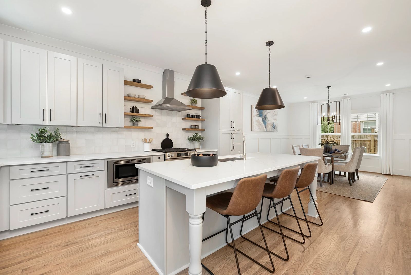 White shaker kitchen with quartz island, black dome pendants and open dining area